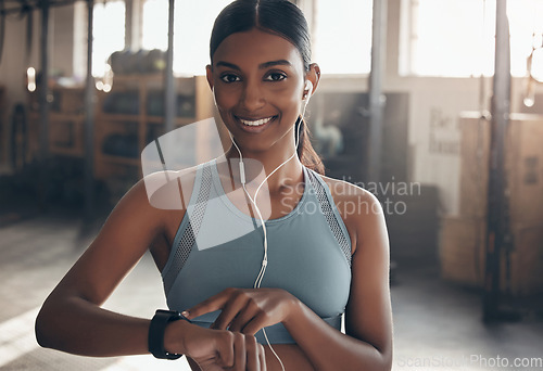 Image of Woman, gym portrait and point at watch, fitness or schedule for workout, training or wellness. Indian girl, personal trainer and time for exercise with smile, music or audio streaming subscription