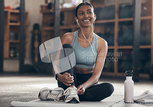 Image of Woman in gym, relax with earphones and fitness, workout and listening to music with smile and sports. Healthy, active with happy Indian female sitting in exercise studio and music for motivation