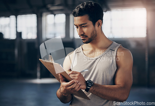 Image of Sports, clipboard and male personal trainer in the gym working on a training schedule checklist. Young, confident and man athlete coach writing workout or exercise plan for wellness in fitness center