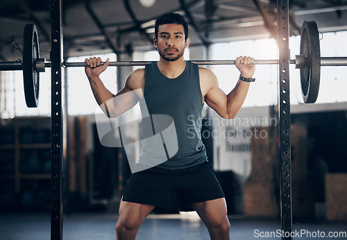 Image of Portrait, exercise and man with barbell in gym for fitness, strong muscle power or health. Bodybuilder, training and face of male athlete weightlifting for wellness, sports and serious squat workout.