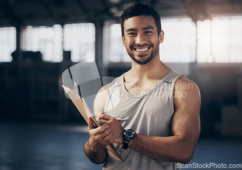 Image of Fitness, clipboard and portrait of a personal trainer in the gym working on a training schedule. Confidence, happy and male athlete writing a workout or exercise plan for wellness in a sports center.
