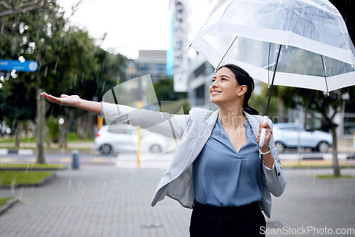 Image of Rain, happy and woman in winter with an umbrella or cold weather in a city street or road and travel in urban town. Corporate, young and employee walking in happiness with a smile in the morning