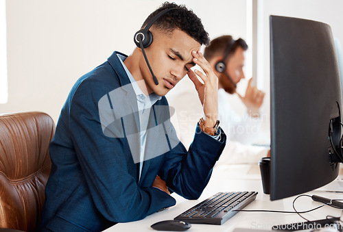 Image of Mental health, man with headache and headset with computer at his desk of a modern office workplace. Telemarketing or customer service, burnout or depression and male person sad at his workstation