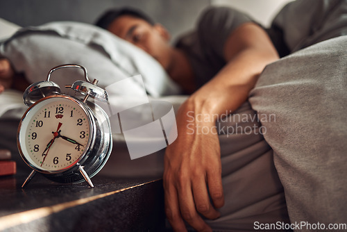 Image of Alarm clock, relax and man sleeping in the bed of his modern apartment in the morning. Lazy, resting and closeup of a timer bell with a male person taking a nap and dreaming in bedroom at his home.