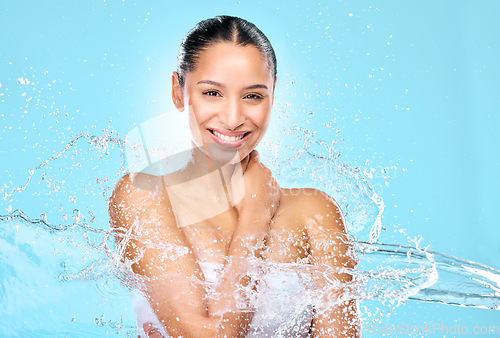Image of Water, splash and beauty with portrait of woman in studio for hygiene, shower and skincare. Wellness, cleaning and fresh with face of female model on blue background for spa, cosmetics and liquid