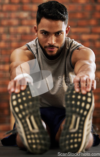 Image of Gym, portrait of man stretching legs and warm up, workout motivation and fitness mindset with hands on feet. Training, commitment and male athlete on floor, stretch at sports club for exercise goals.