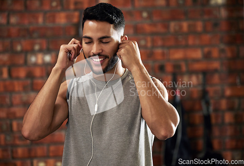 Image of Fitness, earphones and music, man in gym listening to streaming service for motivation podcast and smile. Exercise, workout and happy bodybuilder, online radio or audio for healthy mindset in club.