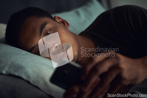 Image of Night, bed and tired man with phone, internet scroll and social media post or texting, insomnia in home. Wake up, browse and exhausted male in dark bedroom with cellphone, mobile game or digital app.