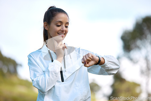 Image of Fitness, watch and heartbeat with a woman runner outdoor checking pulse during a cardio or endurance workout. Exercise, health and heart rate with a young athlete looking at the time while running