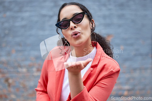 Image of Fashion, blowing kiss and portrait of woman on wall background in trendy, stylish and cool clothes. Beauty, flirt and happy female person pose in city with sunglasses, confidence and style outdoors