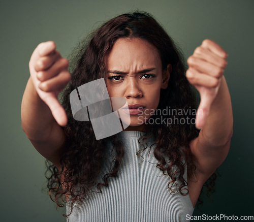 Image of Woman, thumbs down and angry, fail with hands, disagreement and negative mindset isolated on green background. Female person with bad review, feedback and problem with anger and dislike in studio