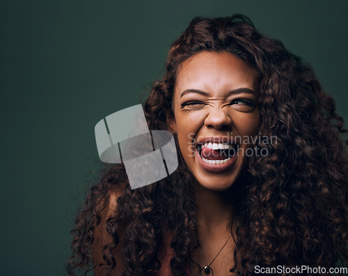 Image of Natural beauty, tongue out and wink by gen z girl with hair, curly and fun on green background. Afro, hair care and female model flirt, emoji and silly face, personality or youth aesthetic in studio