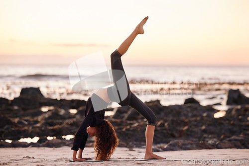 Image of Woman, beach and stretching leg for yoga, chakrasana or sunset for body, health or fitness and mindfulness. Girl. workout and zen meditation for peace, mindset or nature for chakra balance by ocean