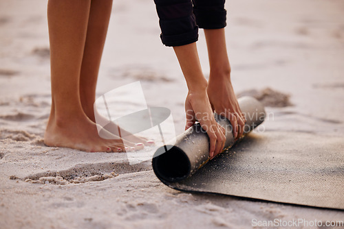 Image of Woman, yoga and beach with hand and feet for rolling mat with clean wellness or fitness. Female person, meditation and yogi on seashore with hands in the outdoor for start in the morning and pilates.