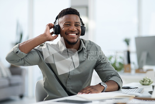 Image of Black man, headphones and listening to music in office with smile for sound track or podcast. Happy African male person or professional designer smiling with headset enjoying audio at the workplace