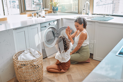 Image of High five, laundry and washing machine with mother and daughter for helping, learning and cleaning. Housekeeping, teamwork and basket with woman and young girl in family home for teaching and clothes