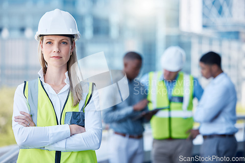 Image of Portrait, arms crossed and a serious woman construction worker outdoor on a building site with her team in the background. Management, leadership and a confident female architect standing outside