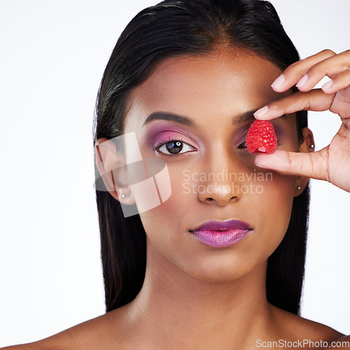 Image of Woman, skincare wellness and raspberry in studio portrait for glow, color makeup or cover eye by white background. Indian model girl, skin health or fruit for cosmetic, healthy nutrition or aesthetic