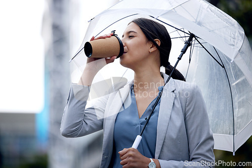 Image of Business woman is drinking coffee, umbrella and travel with commute to work and person in the city. Young female professional in the rain, enjoying hot drink with traveling, urban and insurance
