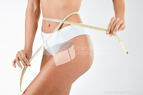 Image of Stomach, tape measure and woman in underwear in studio for diet, detox and healthy lifestyle on white background. Tummy, size and female measuring waist, bmi and abdomen, tummy tuck and results