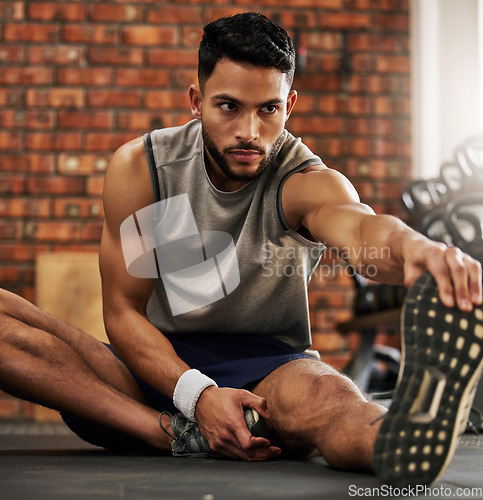 Image of Fitness, man and stretching legs for warm up at gym with motivation, training and focus mindset. Workout, commitment and athlete on floor with hand on foot leg for exercise goals at sports club