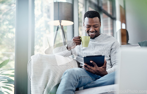 Image of Relax, coffee and tablet with an african man on a sofa, sitting in the living room of his home to browse social media. Smile, technology or internet with a happy male person relaxing alone in a house