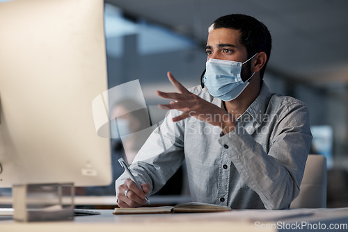 Image of Call center, man and communication with mask at computer while writing notes for advice, customer service and sales. Male telemarketing agent, virus protection and desktop for consulting questions