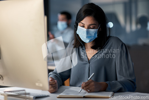 Image of Call center, woman and notes at computer with mask for customer service, sales consulting and CRM in office. Female agent, consultant and virus protection in telemarketing agency for administration