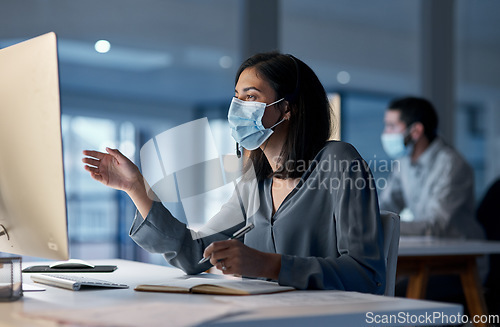 Image of Call center, woman and mask at computer for customer service, telemarketing notes and CRM consulting at night. Female agent, desktop and virus protection for online support, questions and help desk