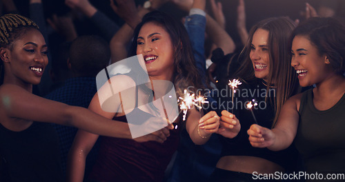 Image of Sparkler, party and night with women in club for music, celebration and nightlife concert. Festival, disco and happy hour with friends dancing in crowd at social event for energy, techno and dj show
