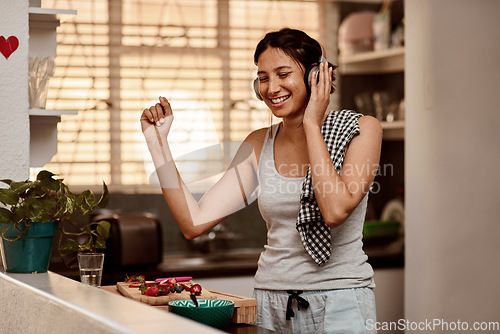 Image of Music headphones, dancing and woman cooking with fruit, strawberry and food. Dance, headphone and female person making breakfast while listening to audio, sound and radio podcast in happy kitchen.