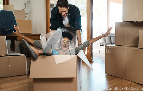 Image of Happy couple, box and fun for moving to new home, real estate property and celebrate together. Excited man, woman and interracial partner playing in boxes at house for freedom, renovation or mortgage