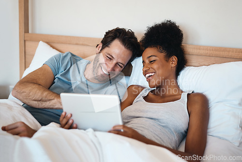 Image of Happy couple, tablet and laughing in bed for funny entertainment, joke or morning in relax together at home. Interracial man and woman person with laugh on technology for social media meme in bedroom