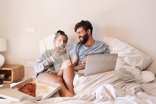 Image of Home bedroom, pizza and happy couple relax, laugh and eating fast food, takeout meal and watch online movie. Happiness, laptop or comfortable people smile, bond and enjoy quality time together on bed