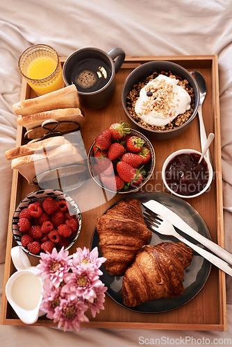 Image of Breakfast in bed, top view and morning food of croissant, strawberry and drinks for wellness, eating and home cuisine. Hospitality, hotel meal service and tray of bread, coffee and juice in bedroom