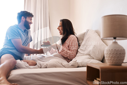 Image of Happy couple, bedroom and surprise birthday muffin, morning dessert or celebration food for excited woman. Cupcake candle, candy and fun people smile, happiness and celebrate special day on home bed