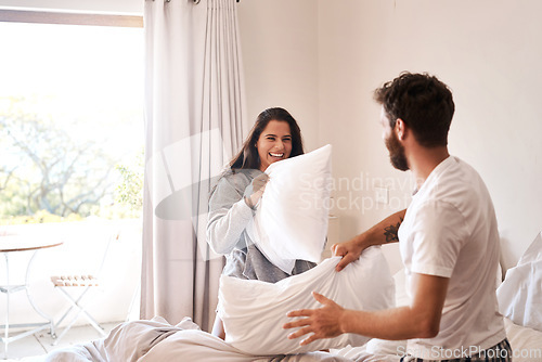 Image of Love, home bedroom and happy couple in pillow fight battle for fun, morning game or playing together. Happiness, excited energy and marriage man, woman or people smile for playful combat on bed