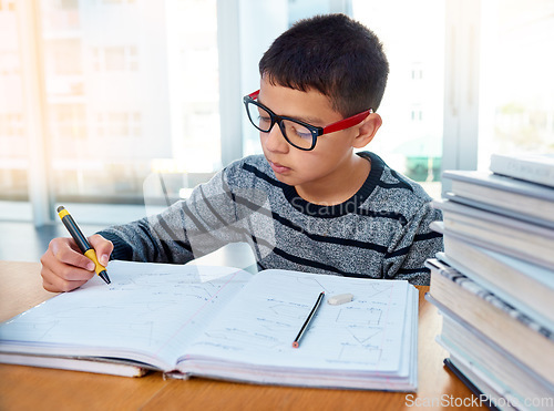 Image of Boy child, student and writing for studying, homework or learning in education with book on table at home. Smart little kid busy on mathematics, textbooks or problem solving for study in living room