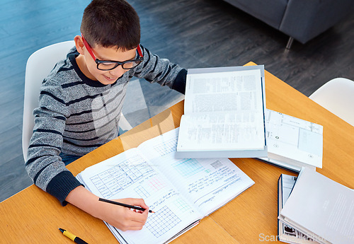 Image of Happy boy, student and writing on math book for studying, learning or education on table at home. Smart little kid or child busy with mathematics homework, textbook or problem solving on study desk