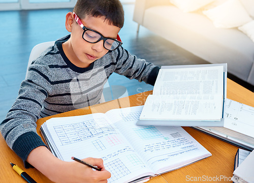 Image of Child boy, student and writing on math book in studying, learning or education on table at home. Smart little kid busy with mathematics homework, textbook or problem solving on living room study desk