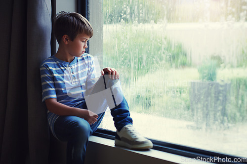 Image of Boy child, rain and sad by window with thinking, mental health and space for mockup in home. Male kid, raining and think by glass with depression, mock up or bored with problem, winter or frustration