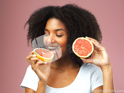 Image of Grapefruit, happy and black woman eat in studio isolated on a pink background. Natural, fruit and African female model eating food for vegan nutrition, vitamin c or healthy diet, hungry and wellness.