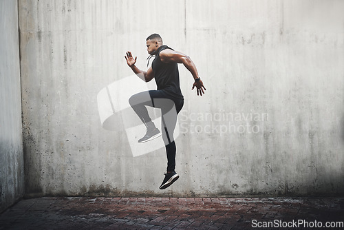 Image of Jump, training and black man running, speed and energy for cardio fitness, workout and sports wellness or body health. Athlete, runner or person exercise on concrete wall, action run or moving in air