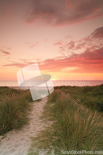 Image of Sunset sky, beach and landscape, nature and travel with environment and coastal location in Denmark. Fresh air, grass and path with seaside destination and ocean view, outdoor and natural scenery