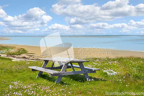 Image of Picnic table, beach and landscape with nature and travel, environment and coastal location in Denmark. Ocean view, fresh air and natural scenery with seaside destination, land and journey with meadow