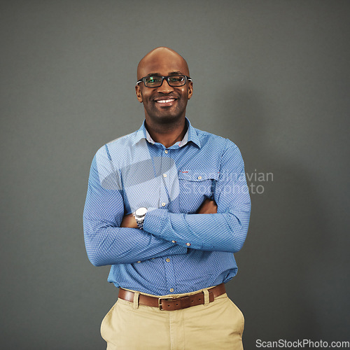 Image of Business ceo, black man and portrait with arms crossed in a studio feeling proud from auditor work. Gray background, smile and African employee with success and leadership vision with glasses