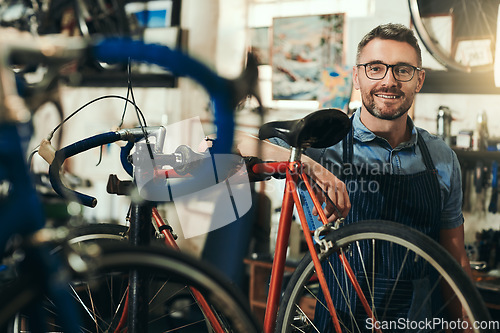 Image of Portrait, happy and repair man in bicycle shop for working in store, cycling workshop and startup. Confident bike mechanic, small business owner and mature male technician with glasses in Australia