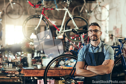 Image of Portrait, serious and repair man in bicycle shop with arms crossed working in workshop. Face, bike mechanic and confident male person, professional or mature technician with glasses in small business