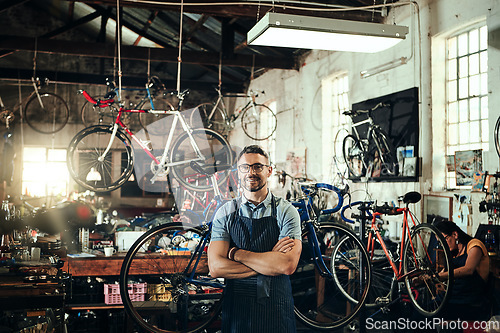 Image of Happy, portrait and repair man in bicycle shop with arms crossed in small business workshop. Owner, bike mechanic and smile of confident person, professional or mature technician and glasses in store
