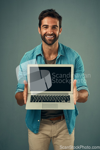 Image of Happy man, laptop and portrait with mockup screen for advertising or marketing against grey studio background. Male person showing technology or computer display or mock up space for advertisement